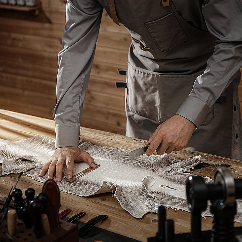 Craftsman cutting exotic leather by hand at the workbench